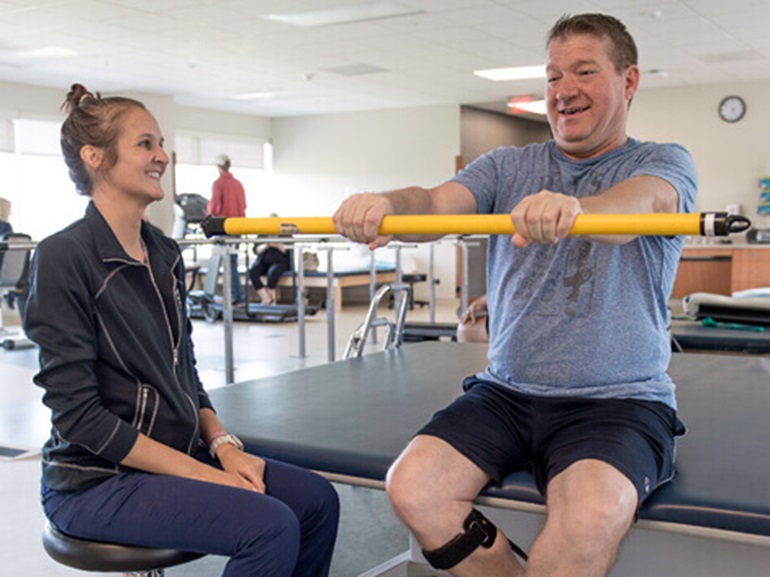Male patient works on strengthening grip during therapy session.