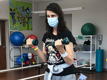 Shelley uses small hand weights as part of her physical therapy to increase arm strength.