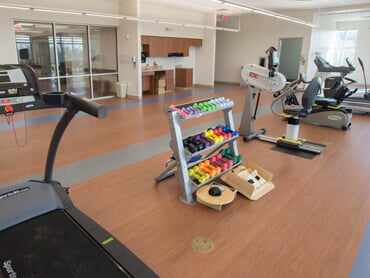 Free weights on a rack and excercise bikes in a therapy gym.